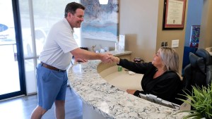 Patient shaking hands with reception staff at the front desk of Stress Free Dentistry office.