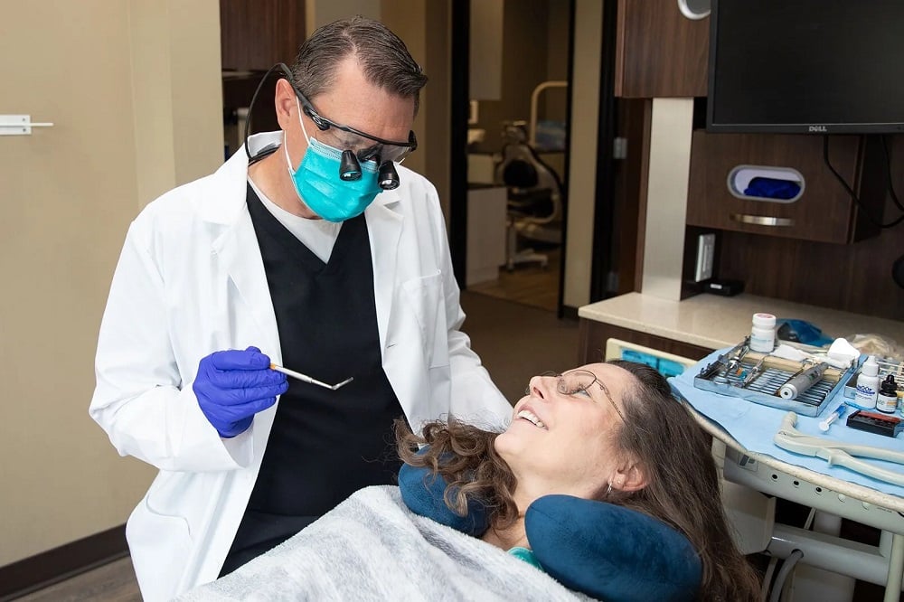 Dr. Stephen Wilson wearing safety loupes and a mask while performing a gentle dental checkup on a patient.