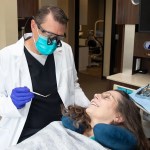 Dr. Stephen Wilson wearing safety loupes and a mask while performing a gentle dental checkup on a patient.