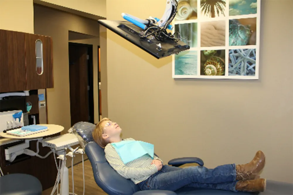 Young patient comfortably relaxing in a dental chair while watching a ceiling-mounted television screen at Stress Free Dentistry.